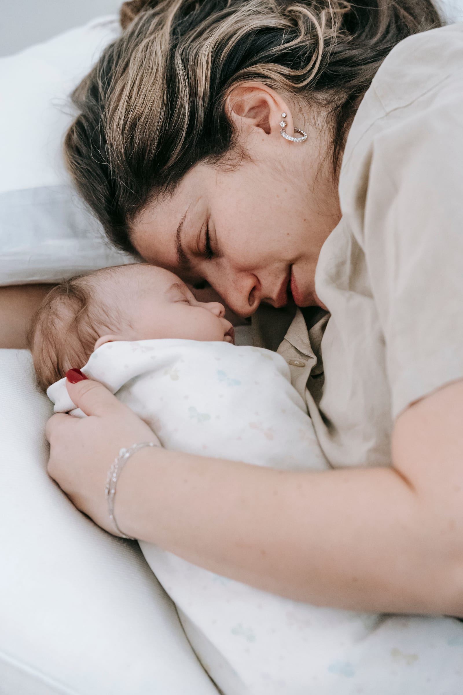 Een moeder ligt wang aan wang met haar slapende pasgeboren baby