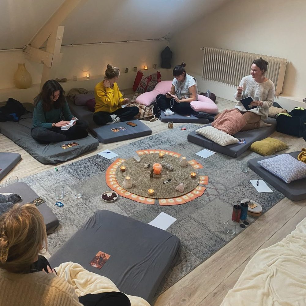 Vrouwen zitten in een cirkel op matten en kussens tijdens een vrouwencirkel bij Studio Rose Moon