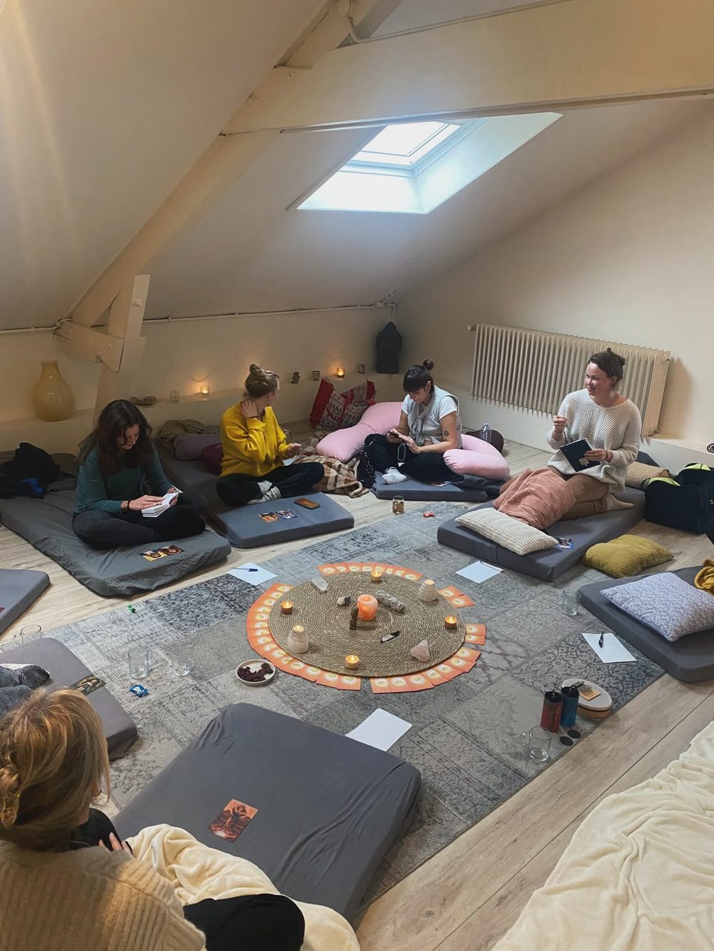 Vrouwen zitten in een cirkel op matten en kussens tijdens een vrouwencirkel bij Studio Rose Moon